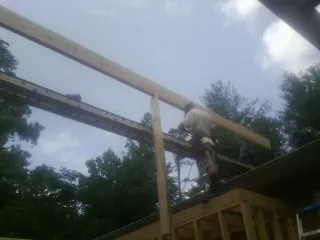 Carpenter setting a ridge beam over a new addition frame — Ice Dam Removal by Roofing Brothers in Wynne