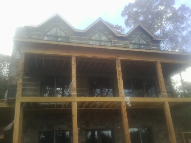 Dormers and porch framing on a large log home under construction — Roof Coating work by our crew in Wynne