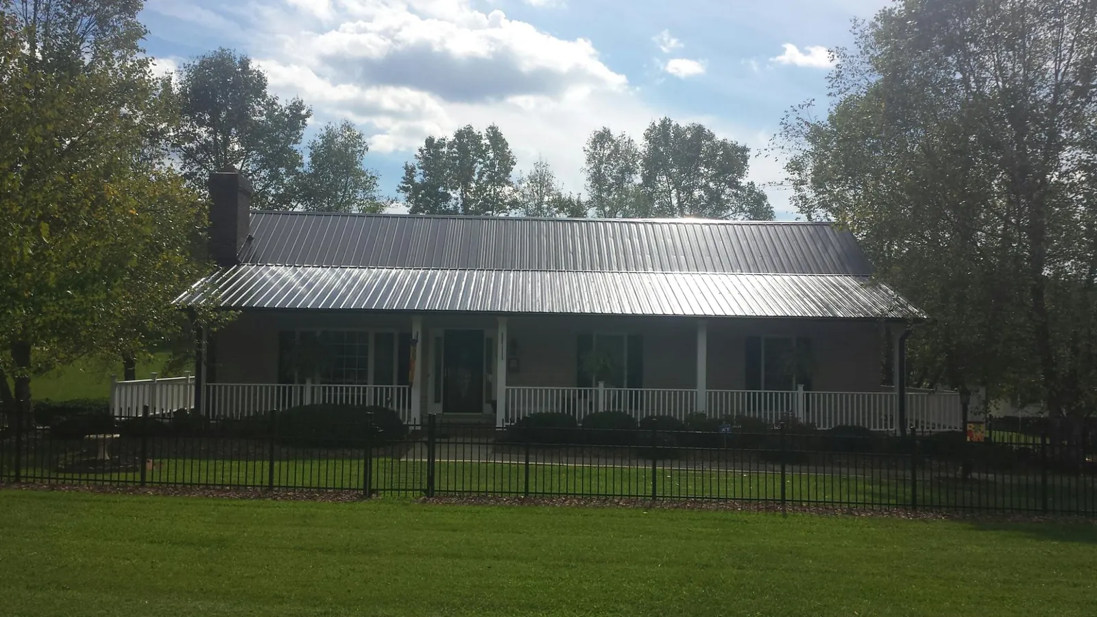 Gray metal roof on a brick ranch with a full width front porch — Gutter Guard Installation work by our crew in Wynne